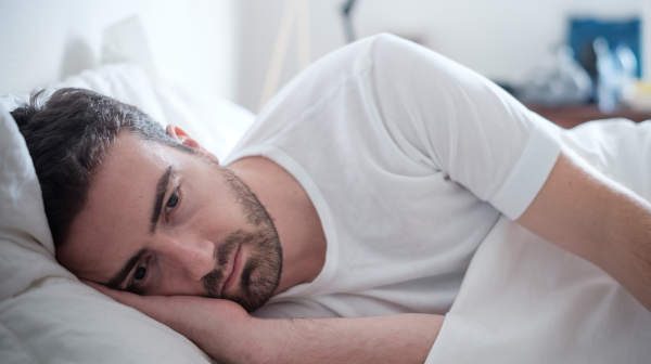 Depressed man laying in bed