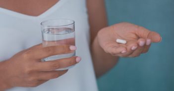 woman holding glass of water and medicine