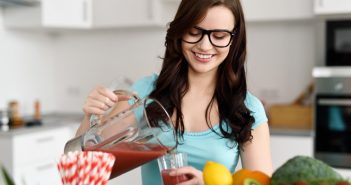Young woman wearing glasses pouring juice